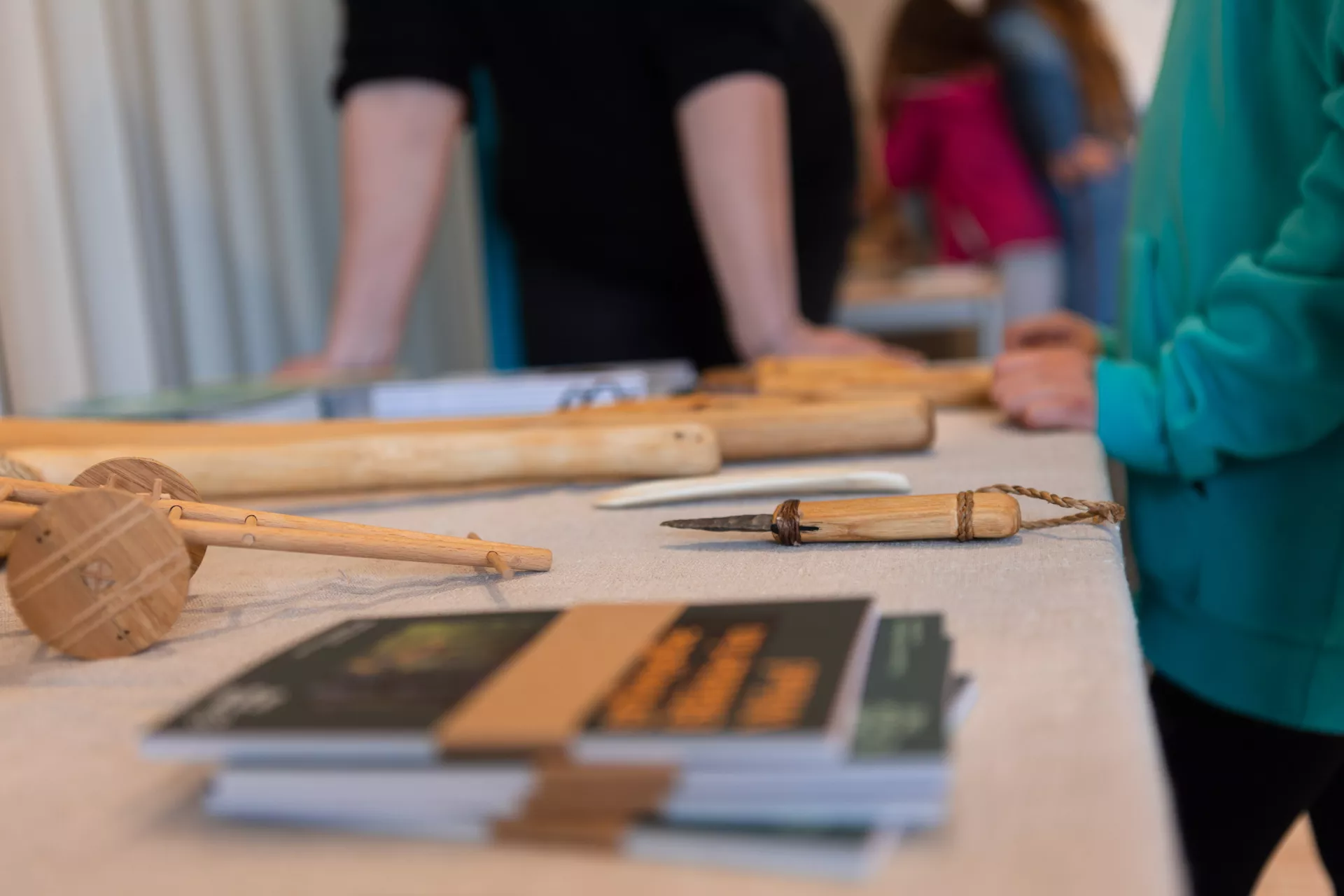 verschiedene Gegenstände aus einer Archäologieausstellung auf einem Tisch. Rund um den Tisch stehen Menschen.