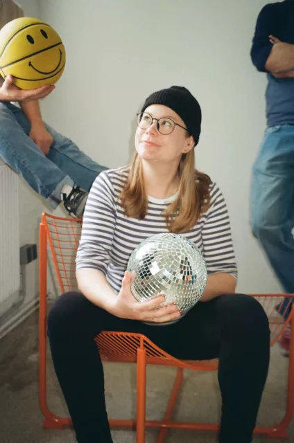 frau auf analogem foto sitzt auf einem orangen stuhl und schaut nach oben