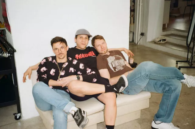 drei männer auf einer couch schauen in die kamera