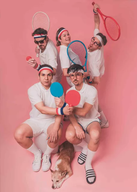 gruppe von fünf personen (ganz in weiß gekleidet) vor einem pinken hintergrund mit tennisoutfits