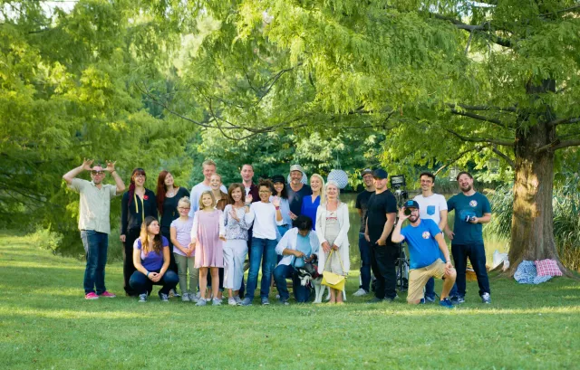 gruppe mit ca 20 personen schaut in die kamera an einem sonnigen sommertag.